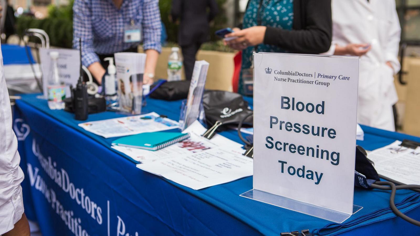 A sign advertising blood pressure screenings on a blue table