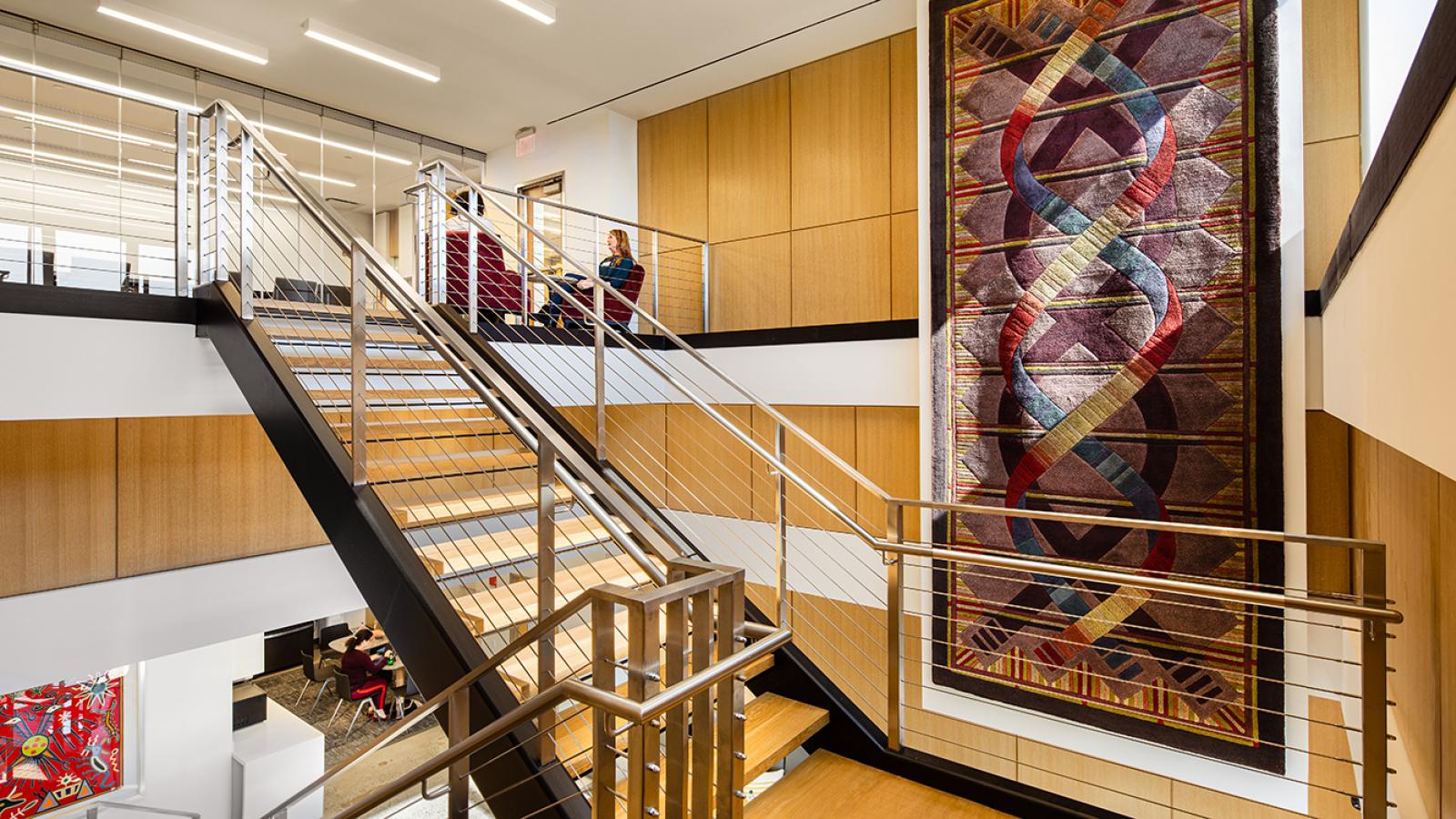 A large, original DNA carpet hangs near a staircase