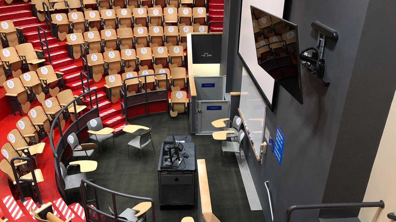 Rows of chairs with stickers on the backs of the seats located in an ampitheater
