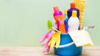 Colorful cleaning tools, such as gloves and sprays and rags, in a bucket