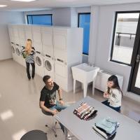 tower 3 laundry room rendering showing washers and dryers, a folding area, and people