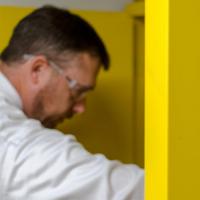 A member of Campus Life Safety and Regulatory Compliance wearing safety goggles while checking a cabinet with flammable liquids