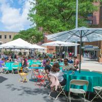 Haven Plaza seating area with tables, umbrellas, and people