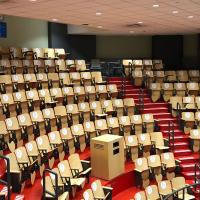 An amphitheater filled with rows of wooden chairs with stickers on the chair backs